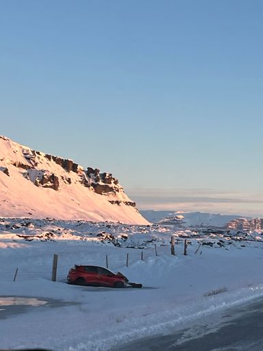 A vertical shot of a red car crashed on the highway in the snow-crashed area