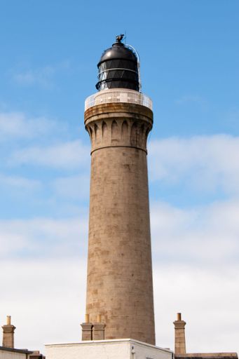 A vertical shot of a beautiful lighthouse against the sky in Highlands, Scotland