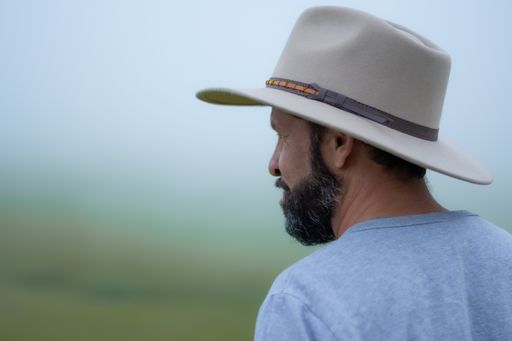 A hispanic man with a hat and beard on vacation in the countryside on a misty d