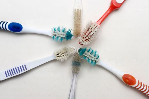 A bunch of old worn out toothbrushes with bent bristles on a white background