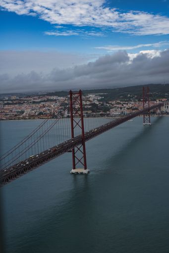 Aerial view of a bridge with white billowing clouds in the background in Lisbon, Portugal