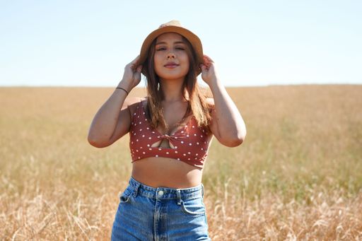 A beautiful Hispanic young woman in a field under a blue sky.