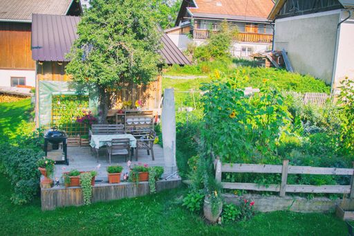You see a countrystyle terrace near to an garden in the tyrolian alps side by side to the garden shed and the barn