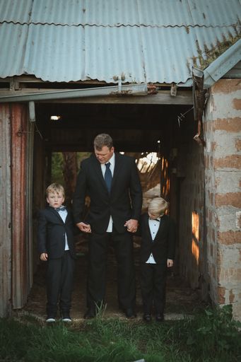 A vertical focus shot of a dad with children in a suit posing at camera
