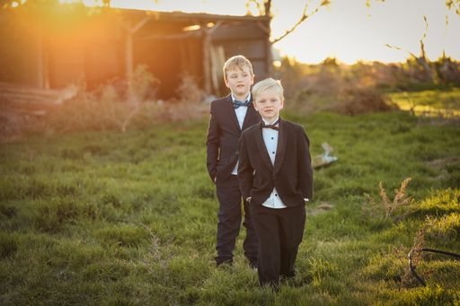 A shallow focus shot of happy brothers in a suit and bow tie posing at camera