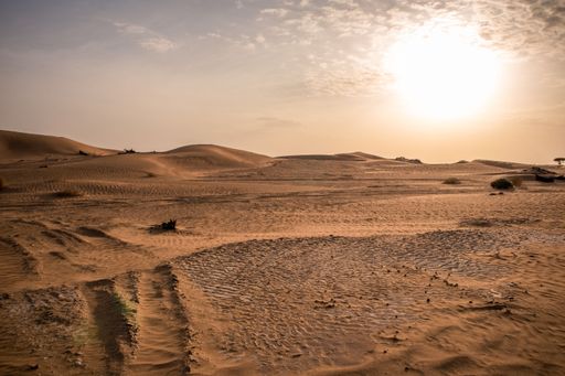 A landscape view of sandy desert dunes with bright sunset sky, for wallpaper