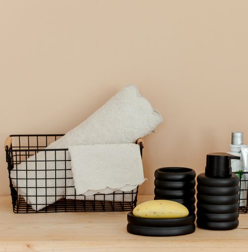 A closeup shot of bathroom towels and soap in a light coral background