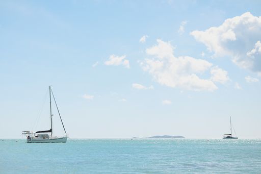 A wide angle shot of an ocean with boats on top under a clear sky,