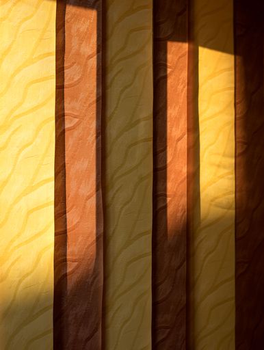 A vertical shot of an orange yellow curtain illuminated by the light