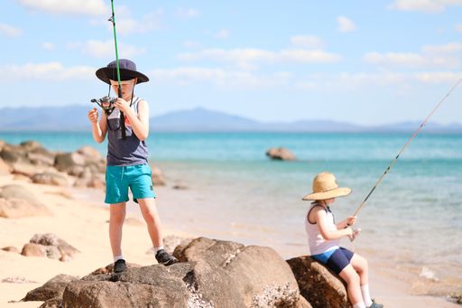 A closeup shot of two white Caucasian young boys fishing on the beach