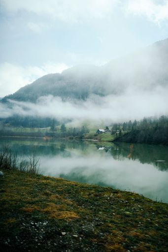 A serene view of zweisimmen montreux golden pass lake surrounded by green mountains on a foggy day