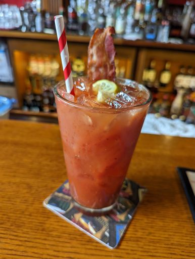 A closeup of a Bloody Mary cocktail over a wooden bar counter