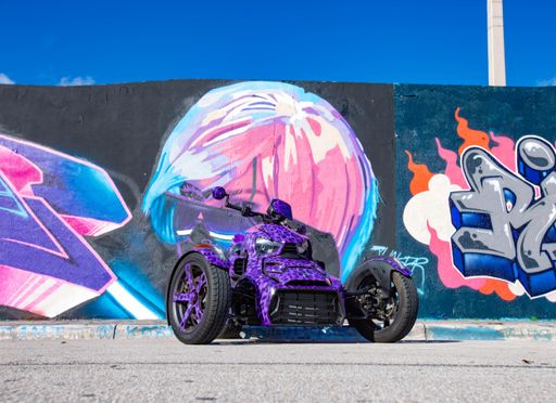 A custom bike parked in front of a wall featuring colorful graffiti and street art