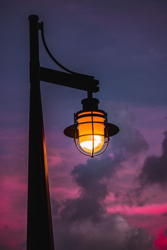 A vertical shot of a lamp outdoor over a purple sunset