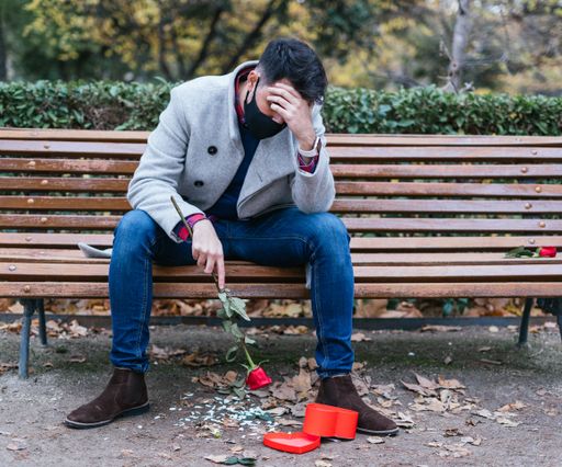 A shallow focus shot of a young male sitting on the bench after losing her love