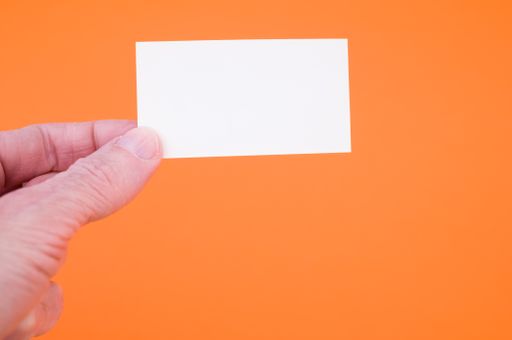 A closeup shot of a person holding a blank paper on an orange background