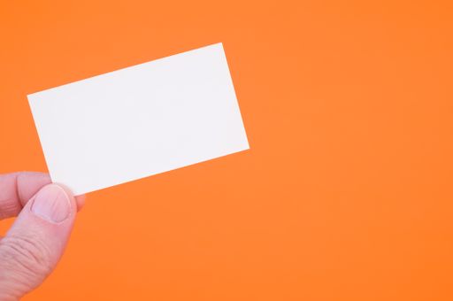 A closeup shot of a person holding a blank paper on an orange background