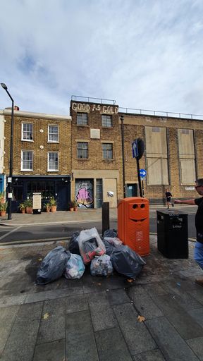 several trash bags on a street in london