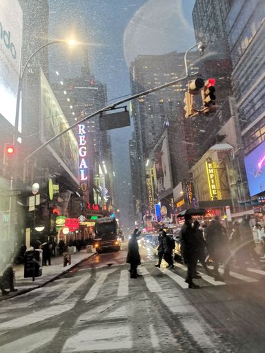 A vertical shot of people crossing the streets at Time Square on a snowy day in New York