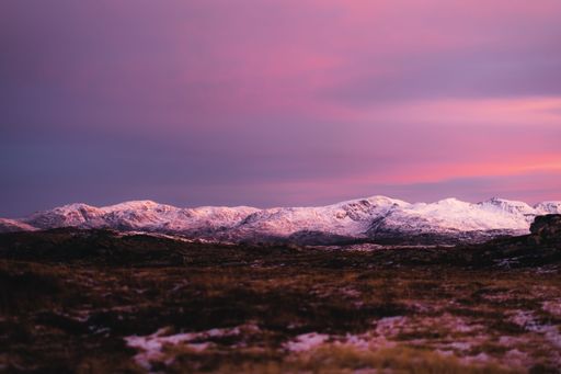 The rocky mountains covered with snow during scenic pink sunset, Tromso, Norway