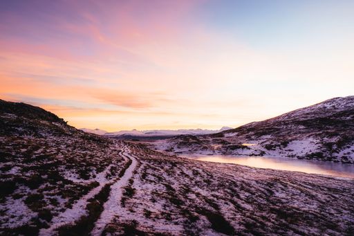 The rocky mountains covered with snow during scenic pink sunset, Tromso, Norway