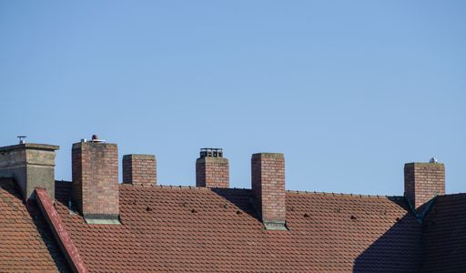 A shingles roof with chimneys against the clear blue sky