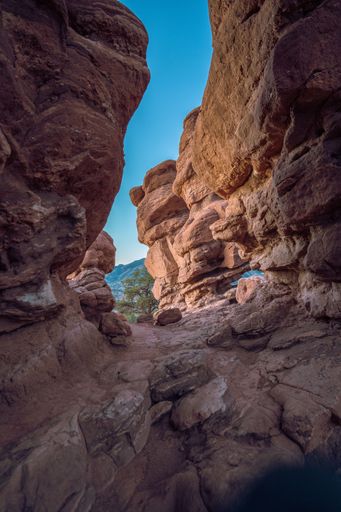 A low-angle shot of a mountain range of Colorado, captured through the rocky formation, on a sunny day, with a blue sky in the background