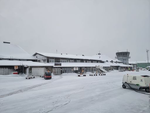 A snow-covered parking zone outside a large airport building