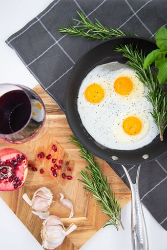 An iron pan with three eggs with herbs and spices, arranged in an aesthetically pleasing arrangement