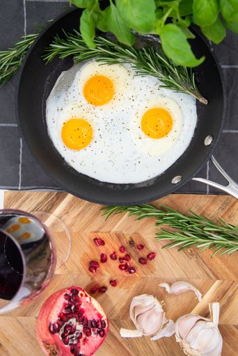 An iron pan with three eggs with herbs and spices, arranged in an aesthetically pleasing arrangement
