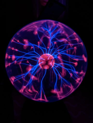A vertical shot of a plasma lamp isolated on the dark black background