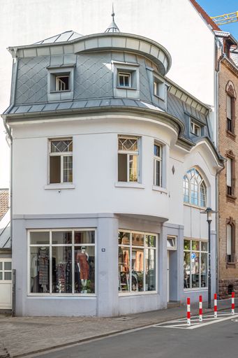An exterior view of a large urban building situated on a bustling city street with vintage architecture
