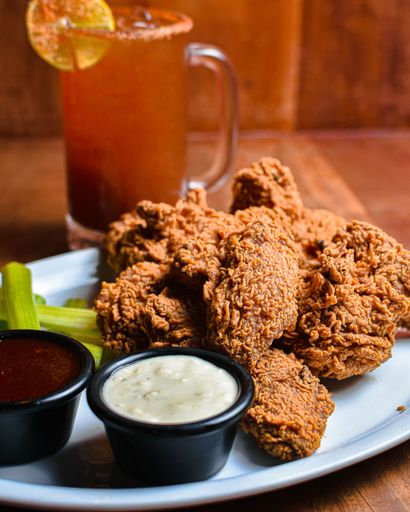 A vertical close-up shot of freshly made delicious grilled chicken wings served with an icy drink