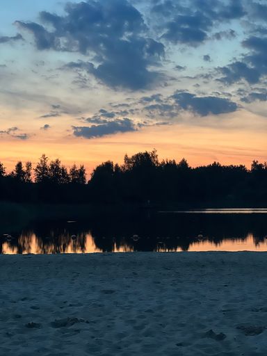 A breathtaking sunset cloudscape seen from the sandy beach over tree silhouettes