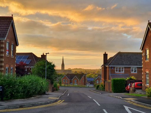 The small similar houses at a calm town in UK with the sunset and an old cathedral in the background