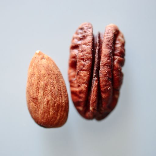 A close-up shot of two halves of an almond nut lying side by side on a white background