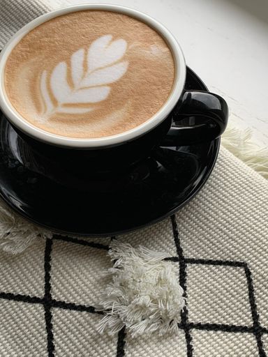 A vertical shot of a cappuccino with a beautiful heart-shaped flower on the foam