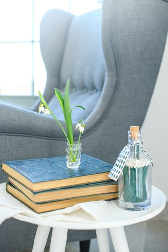 A vertical shot of a comfortable blue armchair near a small table with books in a corner of the house
