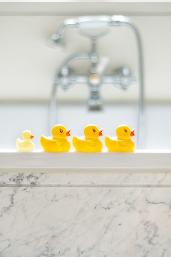 A selective focus shot of cute yellow rubber bath ducks in a row in a bathroom