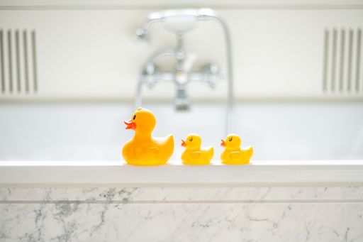 A selective focus shot of cute yellow rubber bath ducks in a row in a bathroom