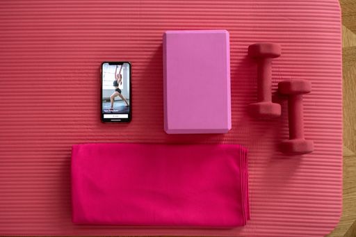 A top view shot of a yoga training essentials with a training program on the phone