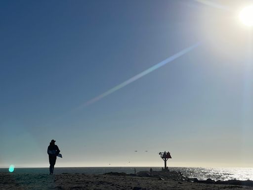 A scenic view of a seascape on a bright, sunny day with a person walking on the beach