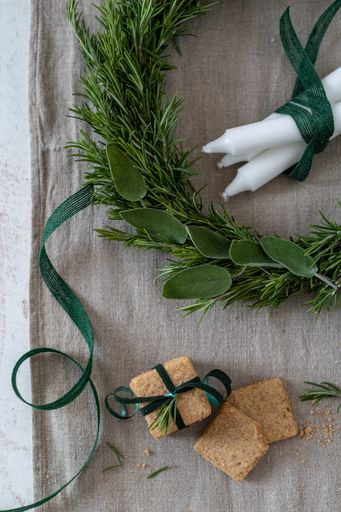 A vertical top view of a Christmas wreath from evergreen leaves, white candles and snacks