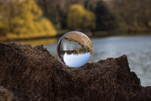 A selective focus shot of a crystal ball on the rock reflecting the lake