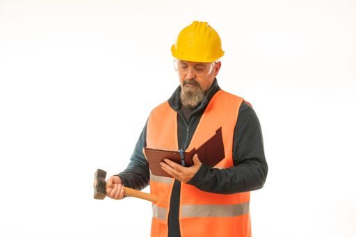 A caucasian construction manager with a hammer and notebook posing on white background