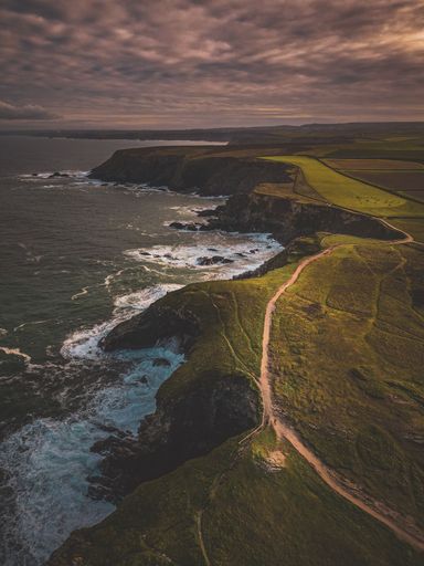 An aerial vertical shot of the rocky mountains in the evening surrounded by the sea