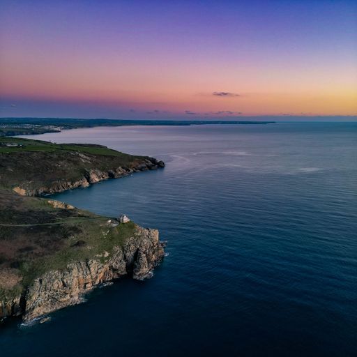 An aerial shot of the mountain with a sea in the background during scenic sunset