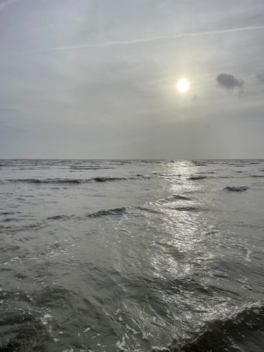 A vertical shot of sea waves of Morecambe Bay under a cloudy sky in Cumbria, England