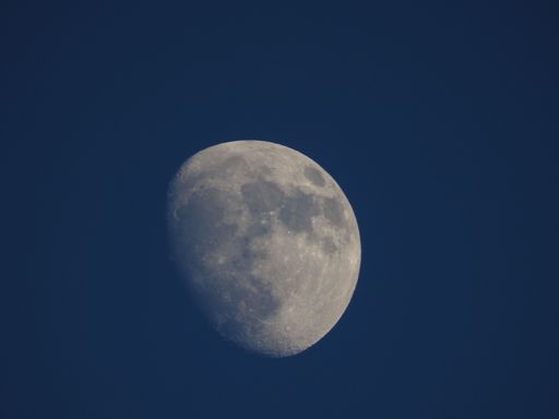 A close up shot of the half-moon in the blue sky