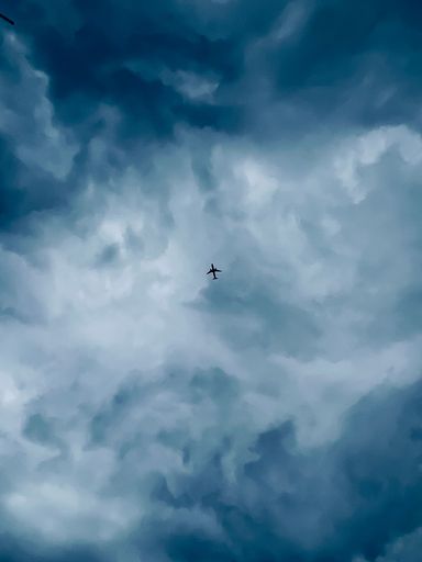 A low angle shot of an airplane flying in a cloudy sky